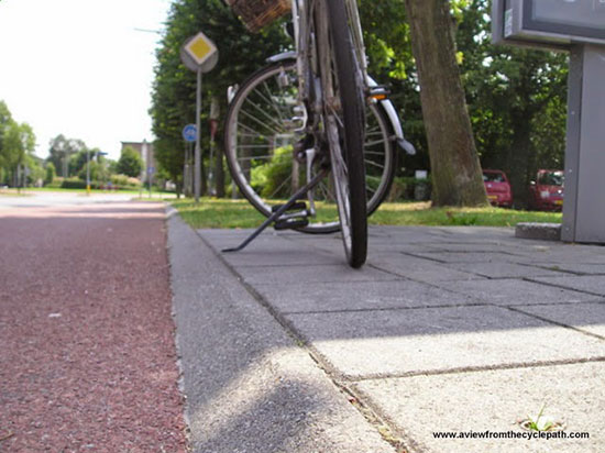 Cat-eye view of a bike next to a forgiving kerb, shallow and angled for safety.