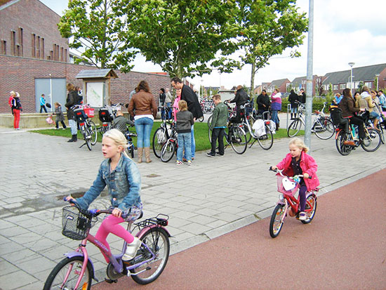 Two young girls ride their bikes home from school on a smooth, wide, motor-free cycleway in the Netherlands.
