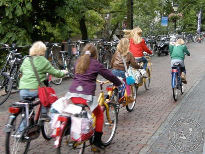 A group of young children ride their bikes along a street in the Netherlands