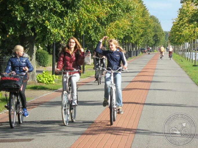 Three teenagers ride alongside each other on a bicycle road