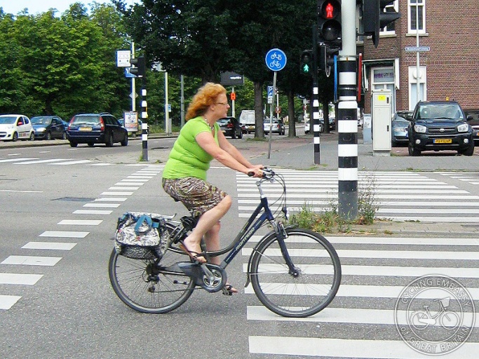 A middle-aged woman rides her bike. No safety accessories needed!
